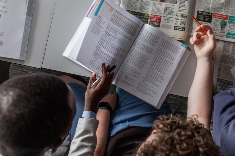 Student and tutor looking at an open book